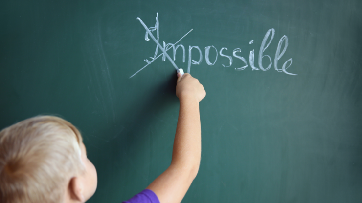 Schoolboy putting a cross over word impossible on blackboard