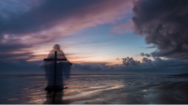 Cross with a faded image of Jesus with a clearing storm at a beach