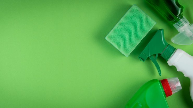 Cleaning supplies on green background, top view