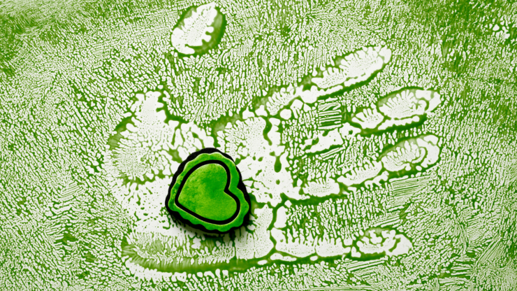 Small green heart on a green painted background with a handprint