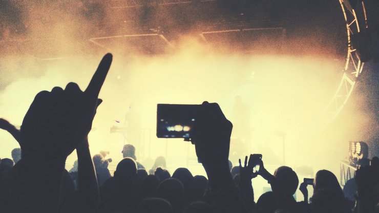 a crowd of people at a concert taking pictures with their cell phones.