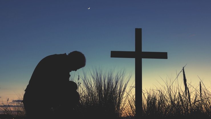 Man praying as a start of a new day begins to dawn