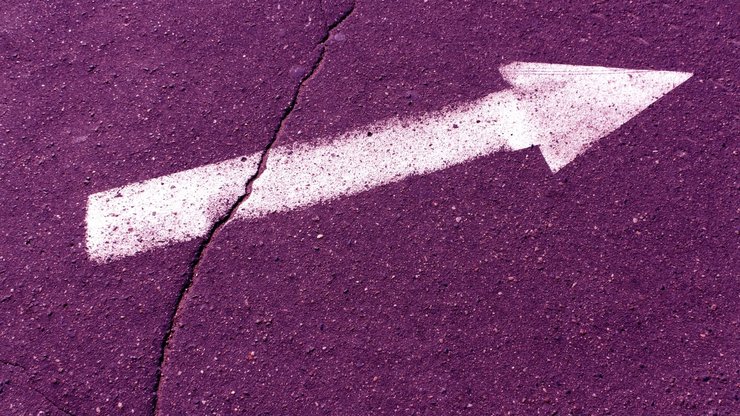 White arrow on purple asphalt surface