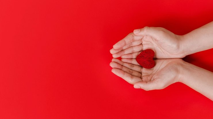 Hands Holding Red Heart on Red Background