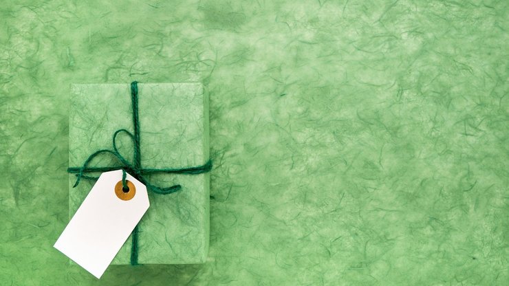 Green gift box with white gift tag on green background